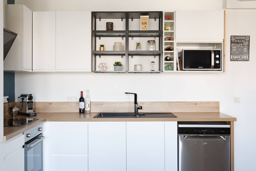 Zoom sur la cuisine blanche, son plan de travail en bois massif, et ses nombreux rangements
