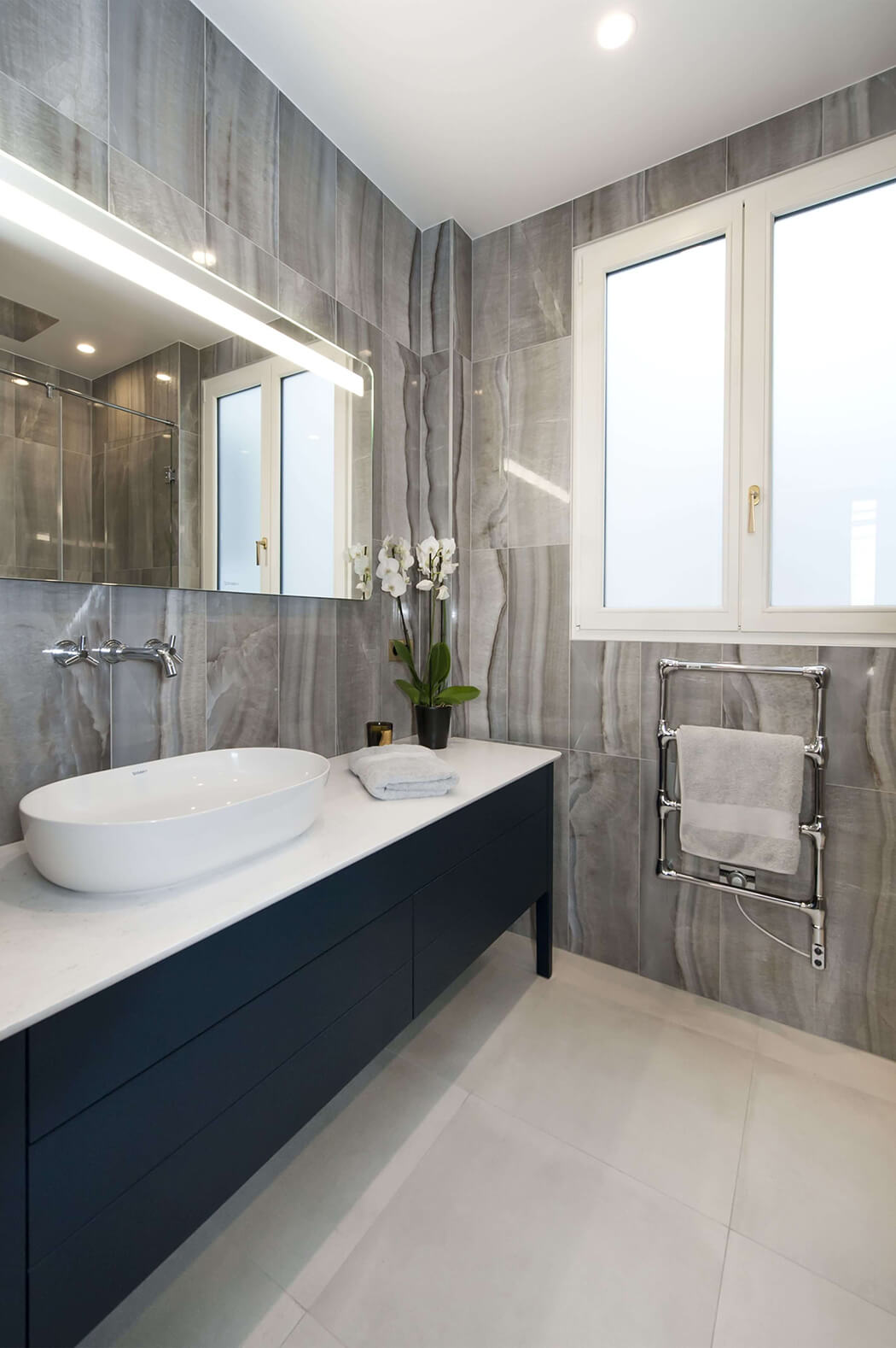 salle de bain de luxe entièrement rénovée avec grand miroir, marbre aux murs et meuble sous vasque anthracite
