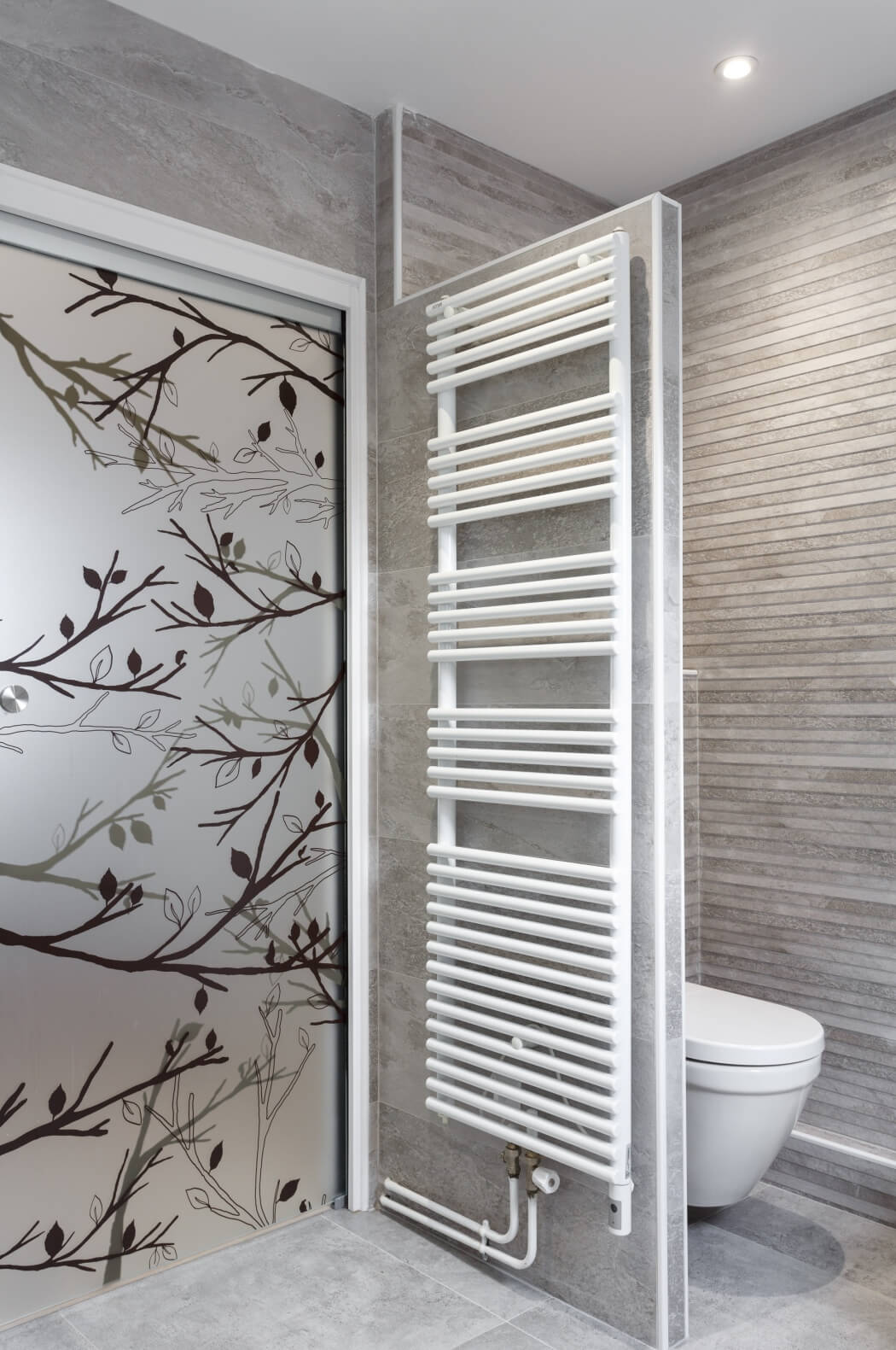 WC suspendu et sèche serviette haut de gamme dans cette salle de bain rénovée aux tons gris