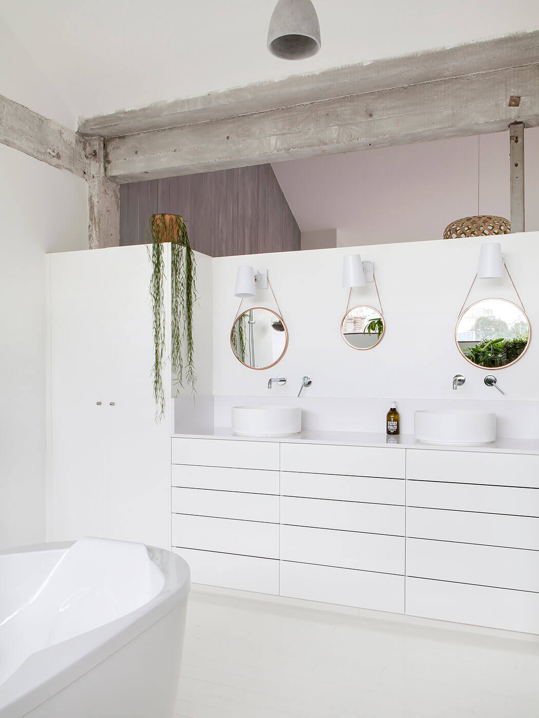 Mélange de modernisme et d'authenticité, avec cette salle de bain au blanc immaculé et ses poutres apparentes